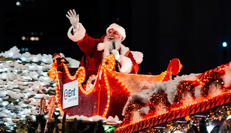 Santa Claus waves to the crowd from atop his sleigh in a parade.
