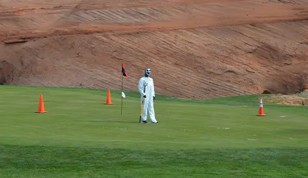A wan in Halloween costume stands on a golf course
